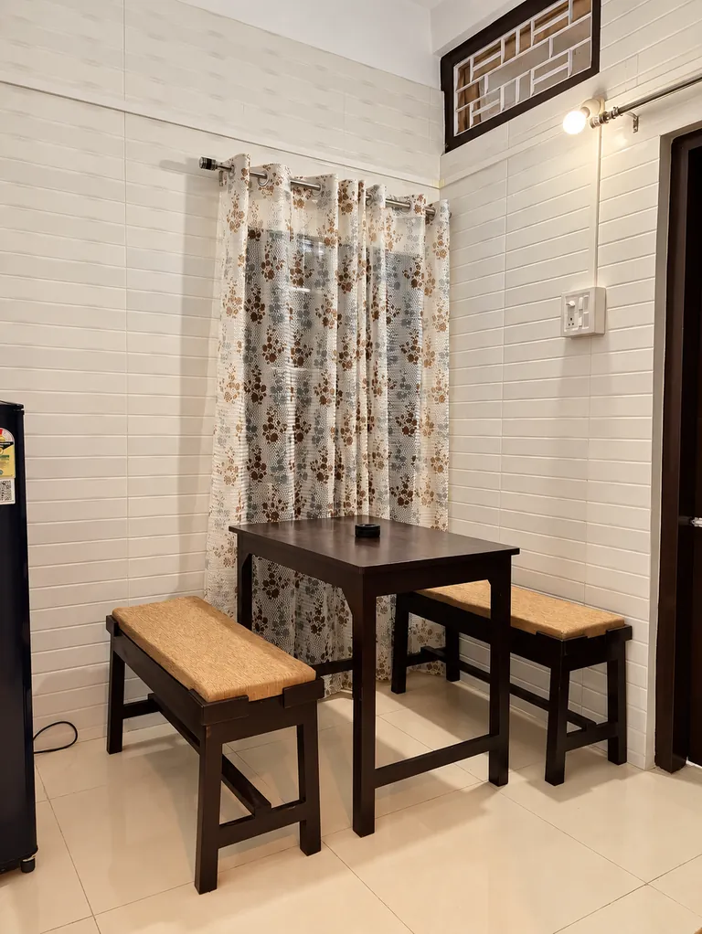 Dining table with two cushioned benches in the 1BHK