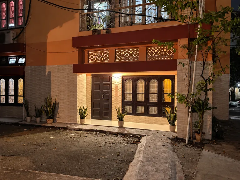 Ground-floor entrance of the Aurum Dwell 1BHK lit in the evening, with potted plants