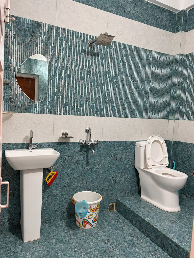 Bathroom in the 1RK with teal mosaic tiles, a washbasin and a shower