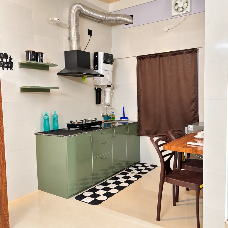 Kitchenette with sage-green cabinets, a chimney hood and a dining counter in the 1RK