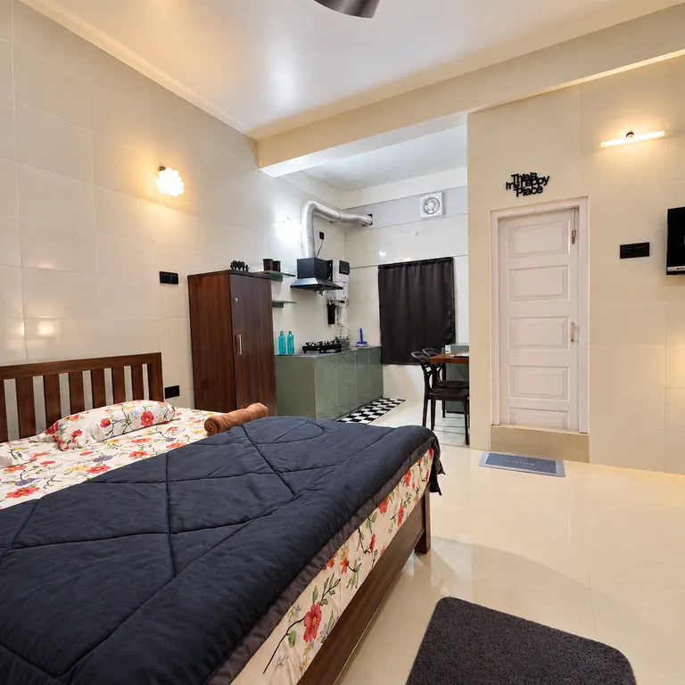 The 1RK room with a king bed, wardrobe and kitchenette, seen from the corner